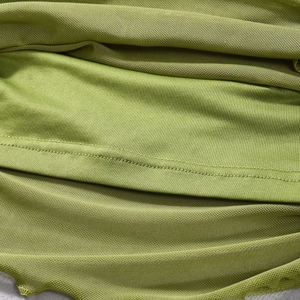 Gros plan détaillé du tissu en maille vert herbe montrant les fronces et les coutures
