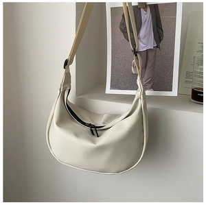 Detail view of a cream-white half-moon hobo bag with adjustable strap and zip closure