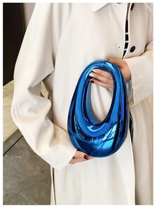 Artistic blue streamlined mirrored clutch bag shown on model against marble background