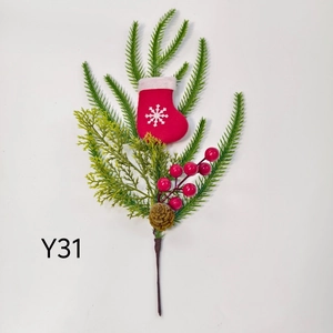 Close-up of artificial Christmas pine branch with red berries and mini snowflake socks