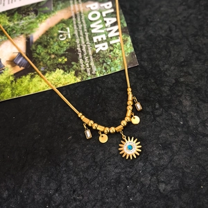 Detail of gold evil eye sun pendant necklace with charms on a textured background