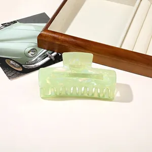 Detail of light green marble texture hair claw clip on a wooden jewelry tray
