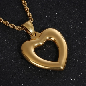 Polished gold hollow heart pendant necklace with twisted rope chain on dark background