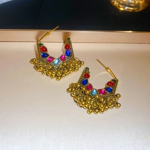 Close-up of ethnic style crescent moon earrings with colorful gems and gold tassels