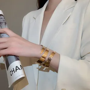 Polished gold multi-layer spiral cuff bracelet styled with white blazer and magazine