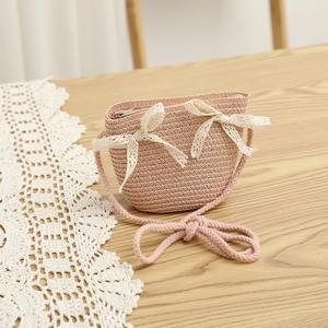 Detailed view of pink straw woven crossbody bag with two white lace bow decorations
