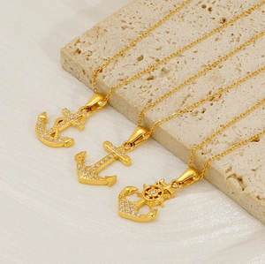 Macro view of gold anchor pendants with zircon inlays on beige stone blocks