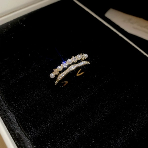 Detail view of double-layered gold ring with four white pearls and shiny cubic zirconia