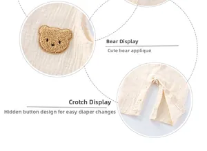 Detail of baby cotton romper featuring brown bear patch and snap button closure for easy diapering