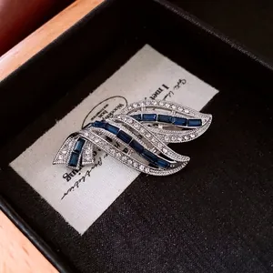 Elegant silver-toned wave brooch with sapphire blue rectangular gemstone and sparkling crystals