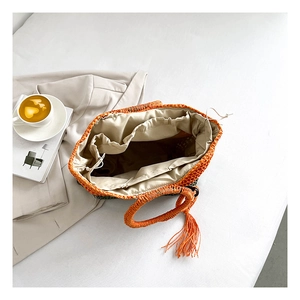 Detail of woven straw bag with orange and green fringe and internal drawstring lining