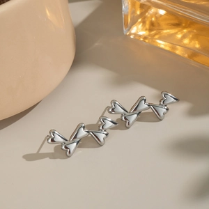 Detail shot of silver stainless steel earrings with linked heart-shaped 3D metal design