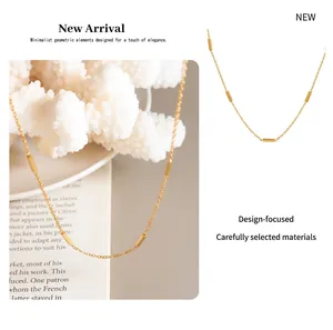 Detail of a minimalist gold collar necklace with geometric bars on coral decor