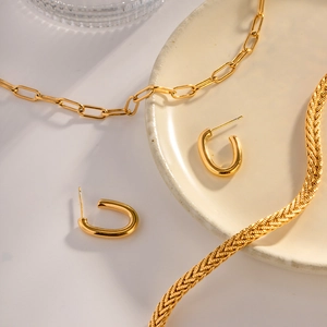 Set di gioielli dorati con orecchini ovali e collana su un elegante vassoio in ceramica