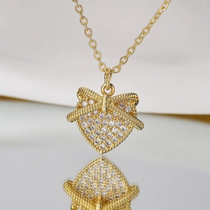 Elegant gold heart pendant necklace with zircon bow on a soft silk background