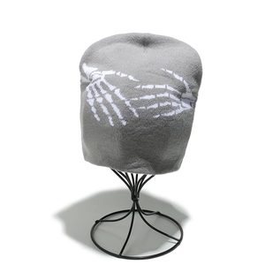 Détail de la texture d'un bonnet gris avec motif de main de squelette blanc sur un support