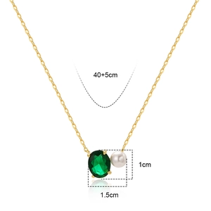 Elegant gold necklace with oval green zircon and white pearl pendant on white background