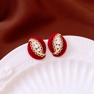 Macro shot of gold-plated oval stud earrings with white pearls and small crystals detail