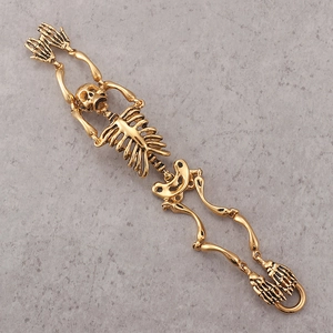 Gothic gold skeleton bone link bracelet in stainless steel on a gray stone surface