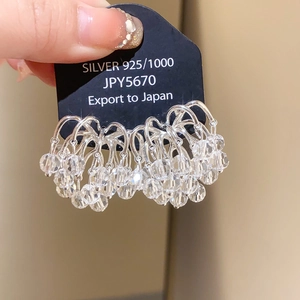 Macro detail of ethnic hollow oval earrings with zircon and silver tassels in hand
