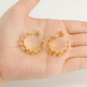 Minimalist 18k gold irregular round link earrings held in palm for size scale