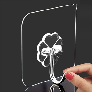 Transparent clover-shaped adhesive wall hook with silver metal hook on black background