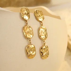 Detailed close-up of textured gold geometric earrings on a ceramic display