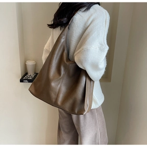 Side view of large brown soft leather hobo bag with wide shoulder strap on model