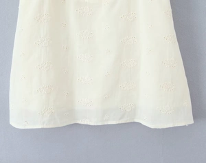 Close-up of white floral eyelet embroidery on puff sleeve dress with lace details