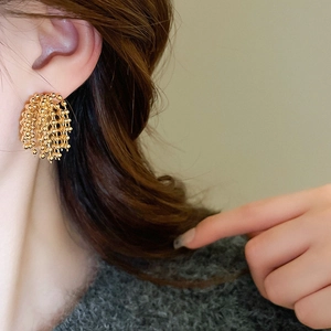 Close-up of gold beaded fringe earrings showing tiered luxury tassel detail on a model
