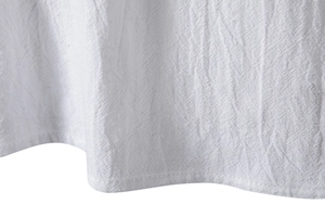 Close-up of white cotton linen fabric showing natural texture and single needle stitching