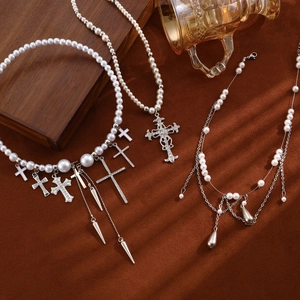 Detail of layered pearl necklaces with cross pendants and tassels on a vintage tray