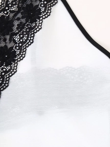 Dettaglio del tessuto in chiffon bianco cucito con delicato pizzo floreale nero