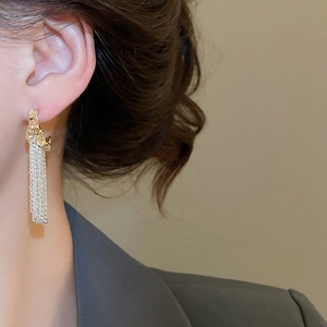 Detail of elegant gold textured C-shape studs with silver metallic fringe tassels