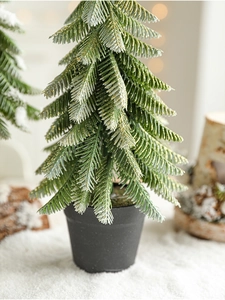 Detailed view of mini snow-flocked Christmas tree with gold glitter and black pot base