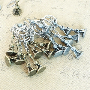 Close-up of bronze and silver tower pendants on metal keychains over textured fabric