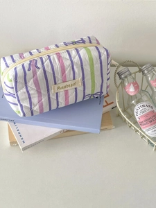 Detailed shot of quilted makeup bag with purple stripes and Purdored logo tag