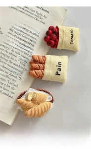 Creative 3D food fridge magnets featuring tomato and croissant on a vintage book