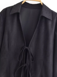 Detail of black suede slim top featuring stylish front bow ties and notched lapel collar
