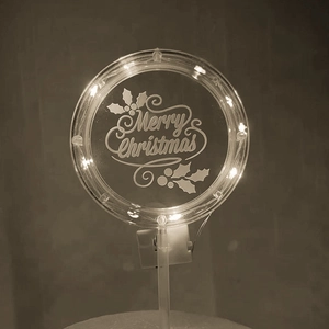 Detail view of acrylic Merry Christmas cake topper with warm LED light and holly engraving