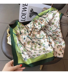 Detailed close-up of a floral butterfly silk scarf featuring a satin green border