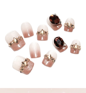 Detail of French cat-eye press-on nails with glitter stones and pink gradient finish