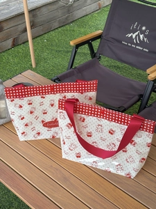Waterproof PVC tote bag with cherry and bear print on a picnic table outdoors