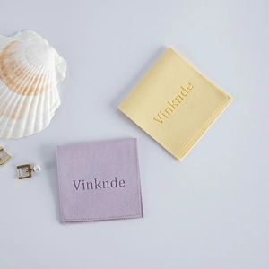 Detailed view of luxury velvet jewelry pouches in pale yellow and lavender with logo