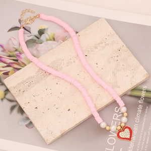 Detail of pink clay bead necklace with red heart pendant and white faux pearls