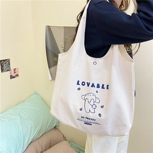 Détail d'un sac cabas en toile crème avec motifs de chiens bleus et bouton pression en métal