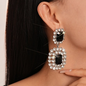 Close-up of luxury geometric rectangular black stone earrings with silver needle studs