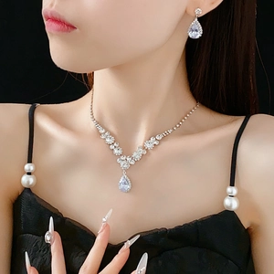 Détail d'un ensemble collier et boucles d'oreilles goutte en zircone sur modèle avec fond noir
