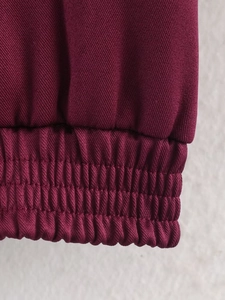 Detail der burgunderroten Bomberjacke mit elastischem Saum und Köperstoff-Textur
