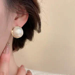 French vintage pearl stud earrings with gold metal edges worn on a model's ear
